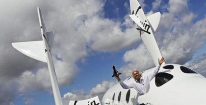 Entrepreneur Richard Branson waves a model of the LauncherOne cargo spacecraft from a window of an actual size model of SpaceShipTwo on display, after Virgin Galactic's LauncherOne announcement and news conference, at the Farnborough Airshow 2012 in southern England July 11, 2012. REUTERS/Luke MacGregor
